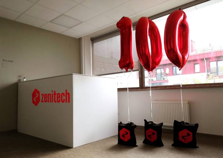 Zenitech logo in red on a counter top with the number 100 in red balloons to the right