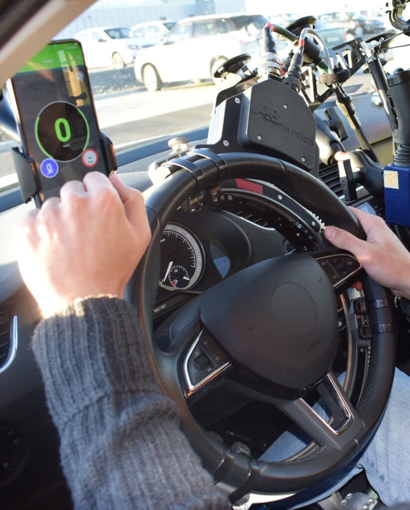 In car view of steering wheel and phone showing Tracker System App