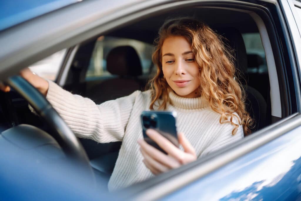 Woman in a car looking at her phone