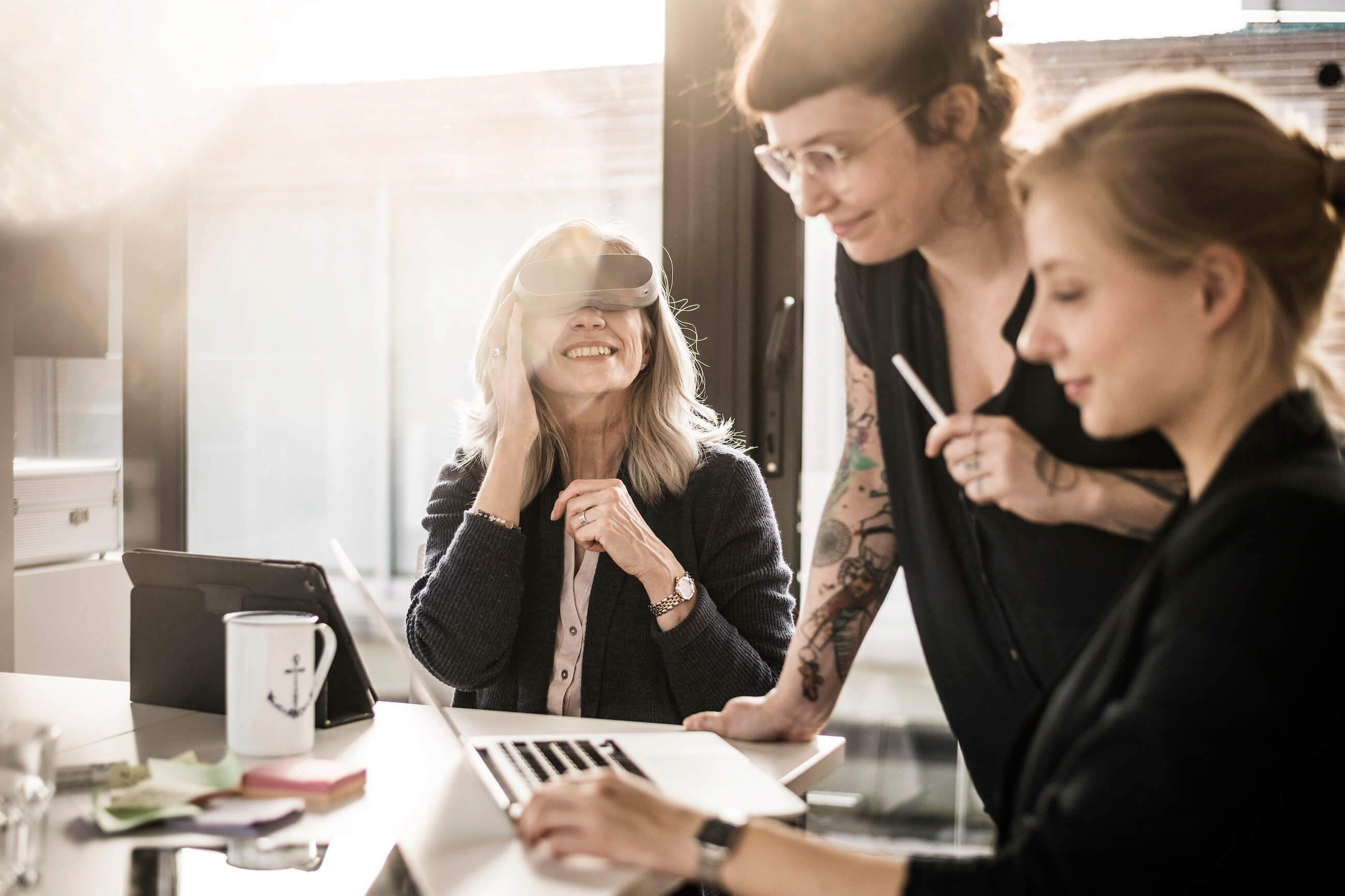 Three people working on a computer, one of them wearing a 3D glass smiling.