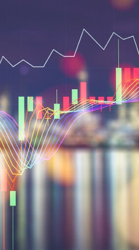 A vibrant financial chart overlaying a blurred cityscape at night, featuring candlestick bars, line graphs, and multicolored trend lines. The image represents energy trading, market analysis, or financial forecasting in a dynamic, high-tech environment.