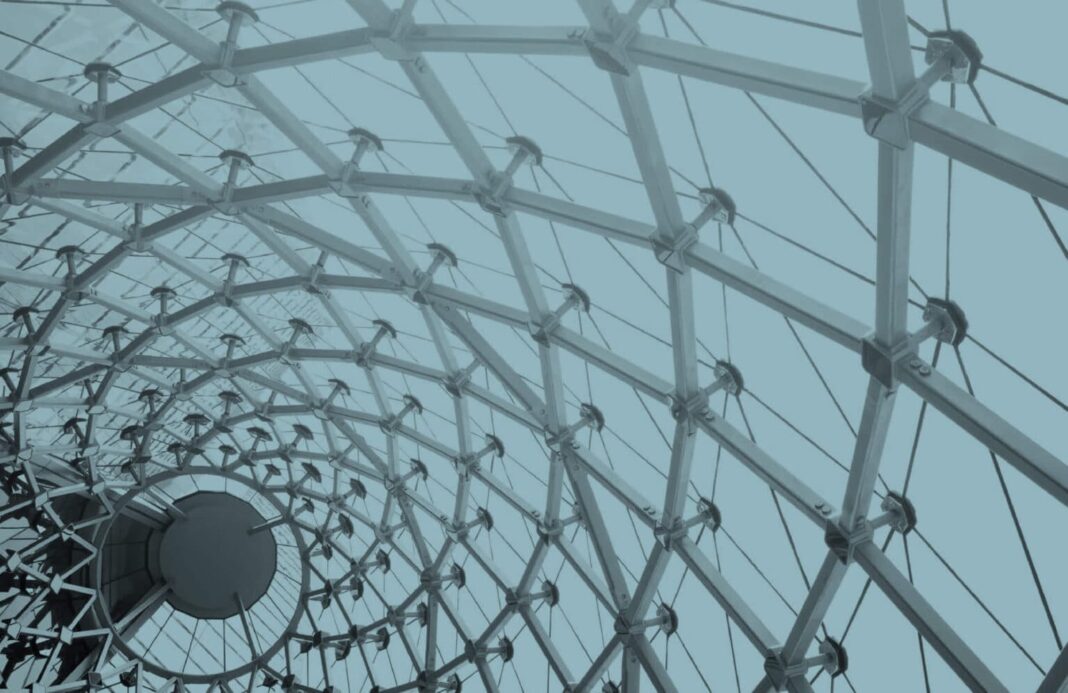 Architectural structure with interlocking metal beams and cables forming a geometric, dome-like pattern, symbolizing modularity and connectivity.