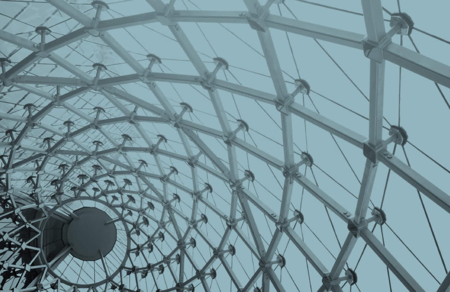 Architectural structure with interlocking metal beams and cables forming a geometric, dome-like pattern, symbolizing modularity and connectivity.