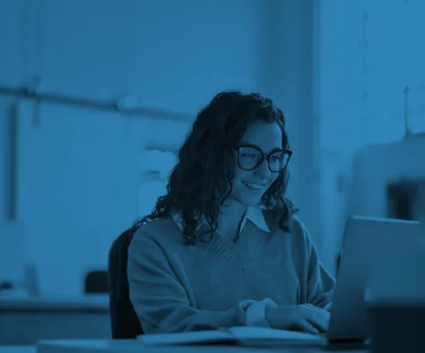 Young woman sat at a desk, researching online