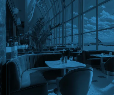 An airport lounge - with large glass windows showing two planes on the tarmac. The image has a blue overlay giving it a blue tint.
